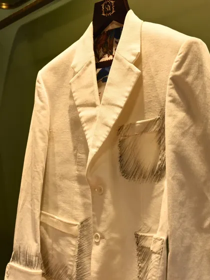 A unique white blazer with artistic, sketch-like embroidery on the pockets and cuffs. This piece is for the client who wants to wear their creativity.