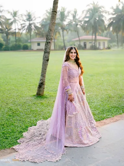 A full-length portrait of the bride in her stunning lavender lehenga with a long, flowing train, captured on the green lawns of the Novotel in Goa.