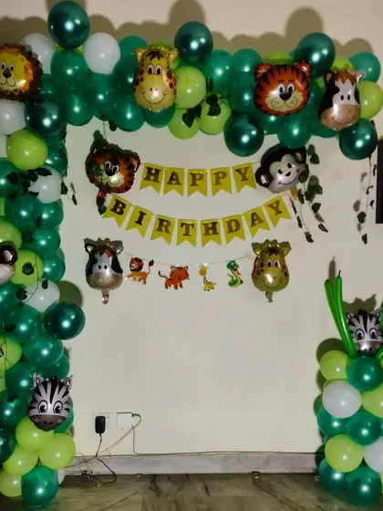 This is a simple and effective jungle-themed balloon arch I set up at home. It features various shades of green balloons and is decorated with multiple animal head foil balloons like a lion, monkey, and tiger.