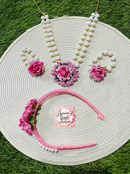 A sweet and simple halwa jewellery set for a child, featuring a necklace, bracelets, and a floral headband. The pink flowers add a playful touch.
