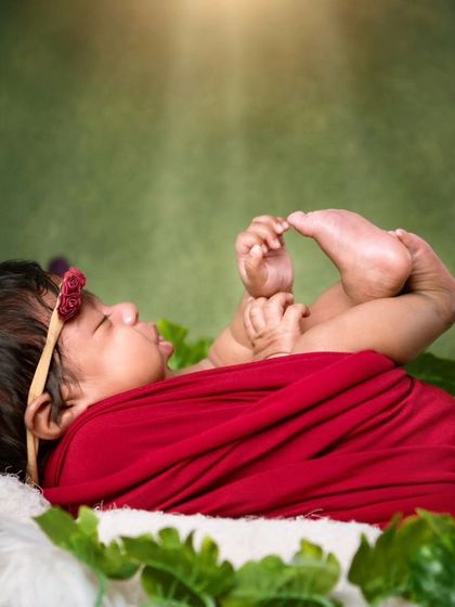 A side view of the newborn holding her feet, a classic and adorable baby pose that we capture safely.