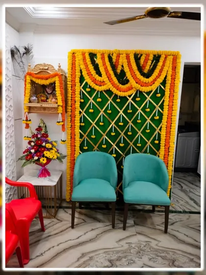 We can create a festive atmosphere even in a small living room. This setup for a home function includes a green backdrop with a marigold toran, a decorated home temple (mandir), and comfortable seating for the ceremony.