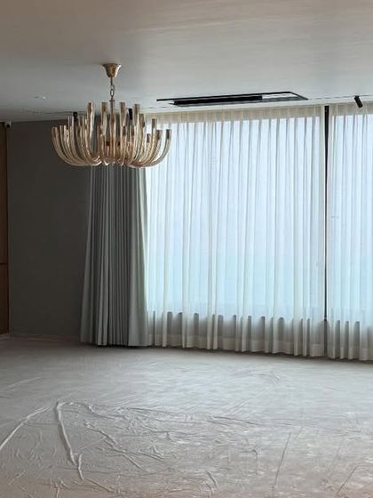 Another view of the living room on handover day, with protective sheets still on the floor. The chandelier and curtains are installed, and the space is ready for the client to move in.