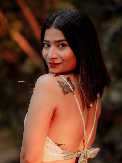 The soft, warm light of sunset enhances this beautiful portrait, highlighting the model's features and the delicate tattoo on her shoulder.