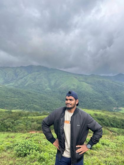 A trekker stands confidently against the backdrop of the expansive Kudremukha hills, ready for the adventure ahead.