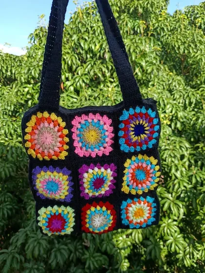 A vibrant granny square tote bag with a rainbow of colors against a black background. This is a statement piece that is sure to sell well.