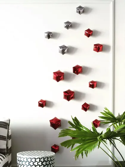 A spray of red and silver metallic cubes adorns the wall, adding a playful and artistic touch that ties in with the red accents in the bar stools and pillows.