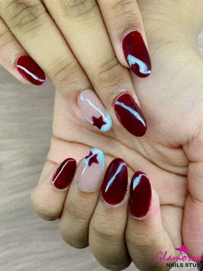A patriotic or simply playful design, this set features rich maroon nails with accent nails showcasing a red star on a nude and blue base.