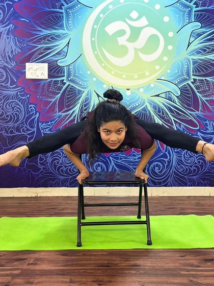 A demonstration of Tittibhasana (Firefly Pose) using a stool for support, showcasing incredible arm and core strength.