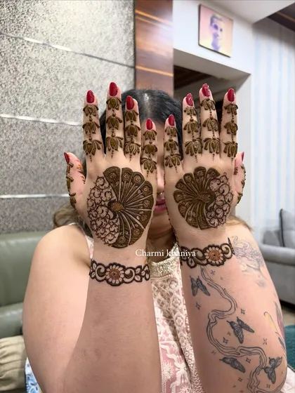 A full view of the peacock mehendi, showing how the two hands create a symmetrical and complete picture. The client's tattoos add a cool, modern edge!