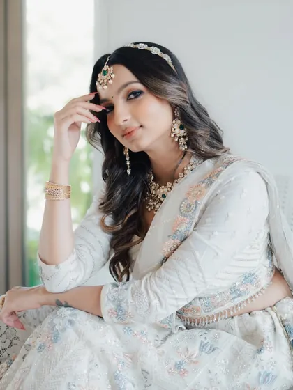 A relaxed and elegant pose, this shot highlights the beauty of the full set, including the maang tikka and matching earrings.