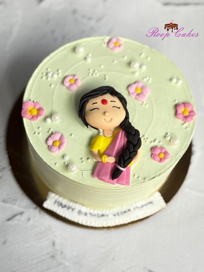 A simple and sweet bento cake made with love for a mother. The light green cake is decorated with small flowers and a 2D fondant figure of a woman in a saree.