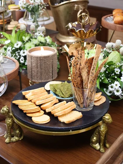 The black marble cheetah-footed stand, styled with crackers and a candle. This versatile piece can be used for serving both sweet and savory treats, adding character to any spread.