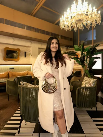 This gold multi-ring handle clutch is pure glamour. It’s designed to be held like a piece of jewelry, making a bold statement against the soft textures of this sequin dress and coat.