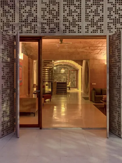 The entrance to the House of Solid Stone in Jaipur, where operable stone screens create a threshold of light and shadow. The entire structure is an ode to a single material, reviving traditional load-bearing techniques to create a modern, climate-responsive dwelling.