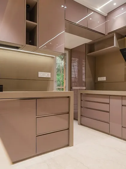 This spacious U-shaped kitchen in Malad features a full back-painted glass finish in a subtle rose gold hue. The layout is designed for maximum efficiency, with plenty of counter space and storage.