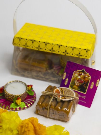 This budget-friendly Diwali hamper includes a stack of handmade Ubtan soaps and a decorative diya, presented in a lovely basket-style box.
