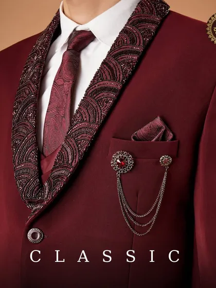 Classic. A detailed shot of the maroon suit's embellished lapel, brooch, and pocket square, highlighting its luxurious accessories.
