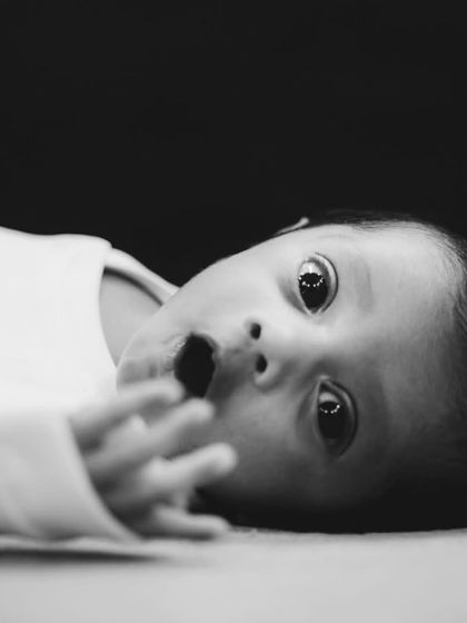 A striking black and white portrait of a newborn with wide, curious eyes. We capture these fleeting moments of wonder, creating powerful and emotive images.