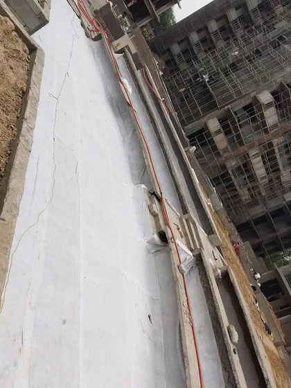 After the drainage cells, we lay down a geotextile filter fabric. This white sheet prevents soil from clogging the drainage system while allowing water to pass through freely.