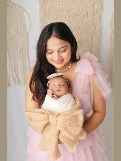 A mother's love shines in this portrait. She holds her swaddled newborn close, creating a memory of those precious early days.