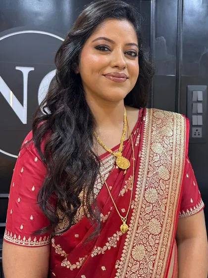 Radiance redefined for a wedding guest. This flawless dewy makeup with a soft smokey eye and nude lip is a timeless choice that looks graceful with her red saree.