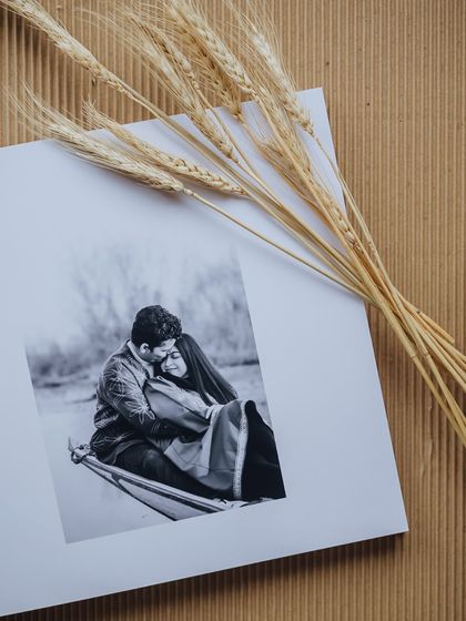 A page from a wedding album, featuring a romantic black and white couple portrait, styled with dried wheat stalks.