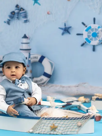 Anchors aweigh for this little sailor's big adventure. We design imaginative nautical themes with custom backdrops and props like this miniature boat and lighthouse to bring your creative vision to life.