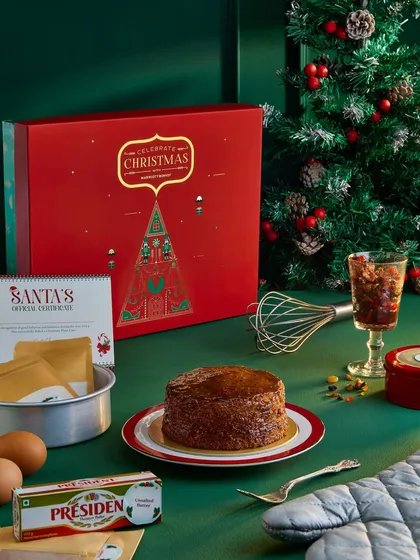 This image highlights a DIY Christmas cake kit from Marriott Bonvoy. By showing the ingredients like eggs and butter alongside the finished cake and gift box, it tells the story of a fun, hands-on holiday activity.