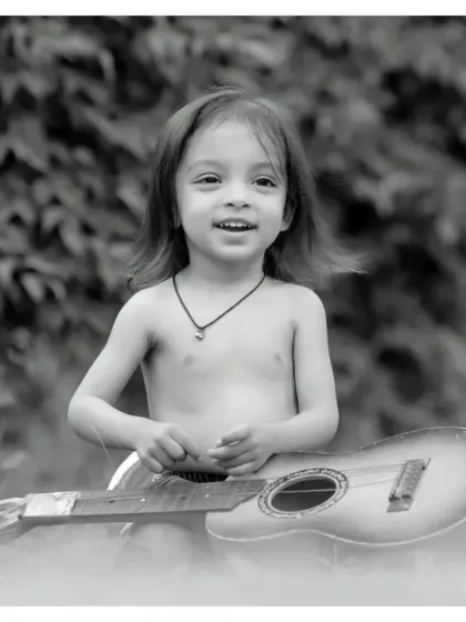 A future musician in the making. This black and white outdoor photo with a guitar has a classic, artistic feel, perfect for capturing a child's passion.