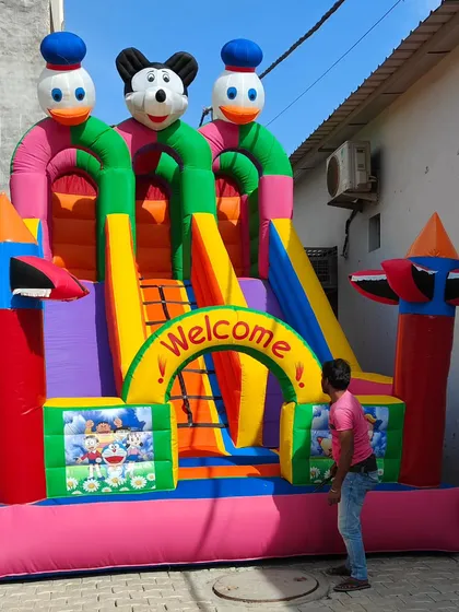 This 12x18 foot 3-slider bouncy shows a person for scale, highlighting its large and impressive size for events.