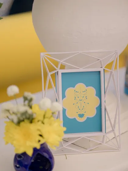 A small, framed graphic with a custom motif, used as a simple yet elegant detail on the tables.