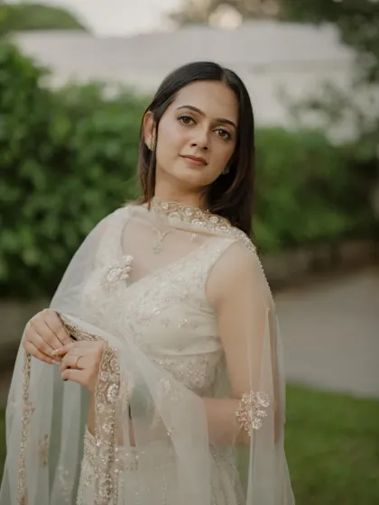 Soft, romantic, and utterly chic. This engagement look features a minimal base, subtle contouring, and a natural lip color to complement her ethereal white lehenga, perfect for an evening of celebration.