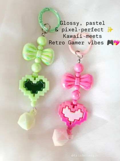 Kawaii meets retro gamer with these pastel pixel heart charms. Available in mint green and bubblegum pink, they feature a cute bow and a geometric bead for a unique look.