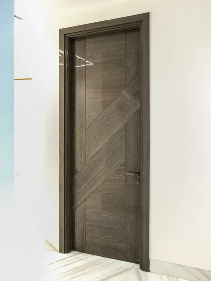 Another view of the Sucupira dyed grey veneer door, showing how it stands out against a clean, white wall. The design is both bold and understated.