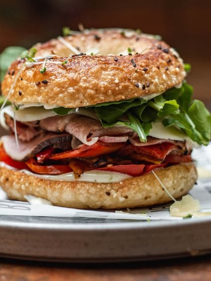A loaded bagel sandwich, packed with cured meats, cheese, and fresh arugula, served on our house-made everything bagel.