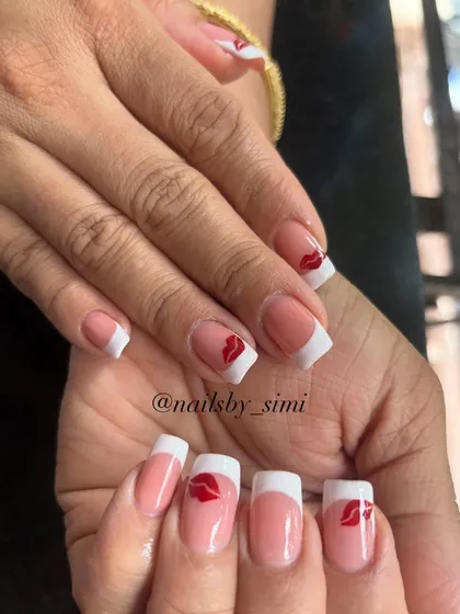 A fun twist on a French manicure with cute little red kiss prints on the accent nails.