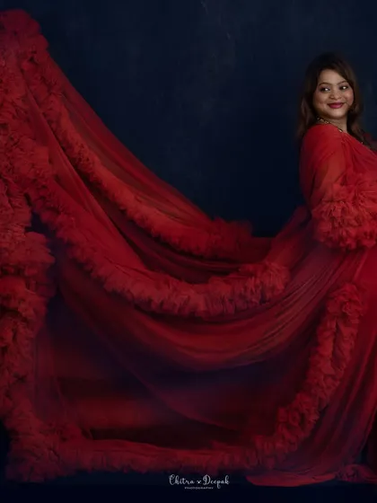 A stunning profile showcasing the incredible train of this red ruffled gown against a deep blue background.