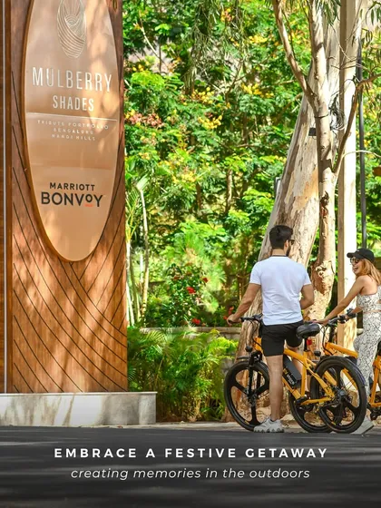 Embrace a festive getaway in the great outdoors. A couple stands with bicycles near our entrance, ready to explore the scenic beauty of the Nandi Hills area.