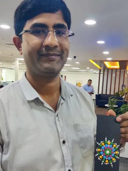 A male employee from the Colliers team shows his colourful dot mandala bookmark. This image shows that art workshops are an inclusive and enjoyable activity for everyone in the workplace.