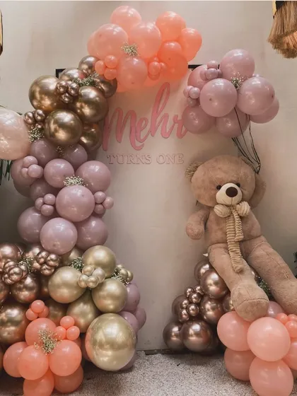 A "one-derful" first birthday for a little princess. This soft and dreamy backdrop for Mehr's big day features a custom name sign, a beautiful organic balloon arch in pastel pinks and rose gold, and an adorable oversized teddy bear to complete the cuddly, elegant theme.