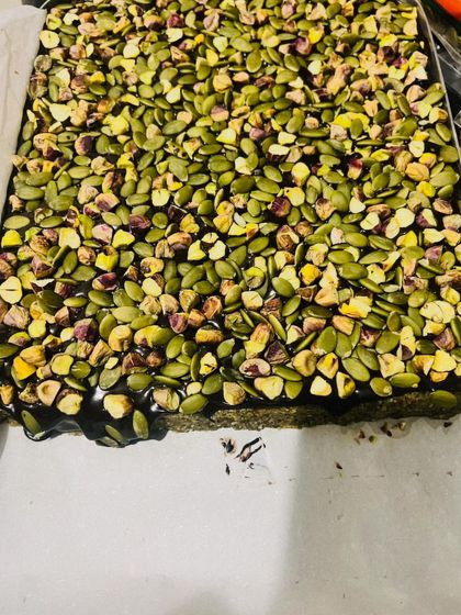 A close-up of my Pumpkin Seeds & Fig bars before they are cut. You can see the dense layer of pumpkin seeds and pistachios over a rich, dark base made from figs and nuts.
