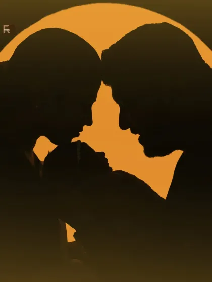 A warm, golden-toned silhouette of a new family. This artistic shot creates a feeling of warmth, love, and protection as the parents gaze at their newborn.