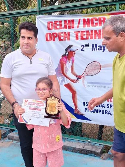 A young player proudly holding her trophy and certificate. These moments build confidence and a love for the game.