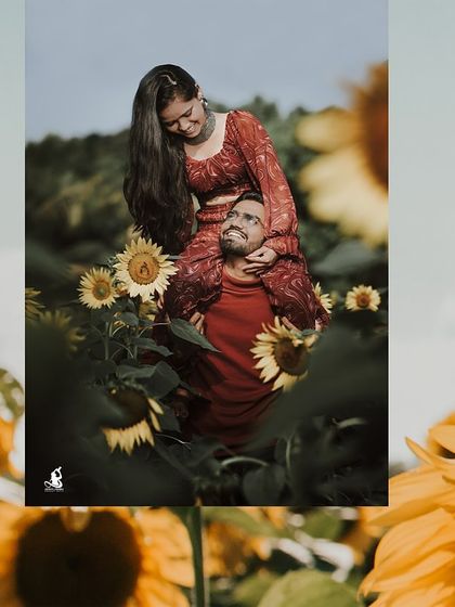 A fun and playful shot of the groom-to-be giving his fiancée a shoulder ride through a field of sunflowers.