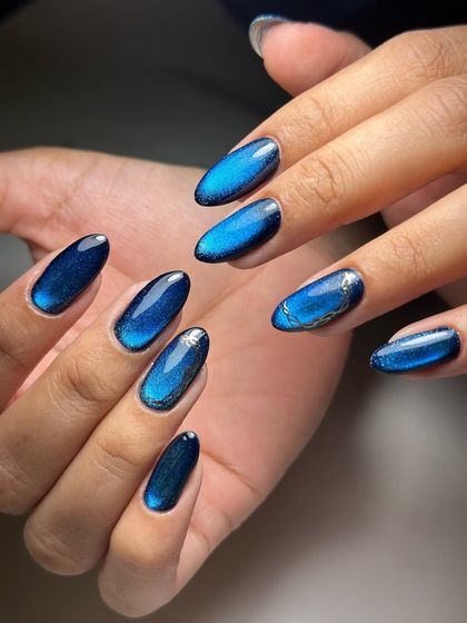 A full view of the mesmerizing blue cat-eye nails, with a subtle silver accent on one nail.