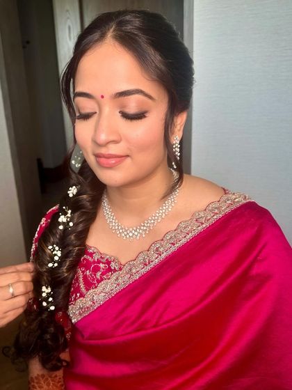 A romantic look in a vibrant pink saree, with a soft braided hairstyle adorned with baby's breath.