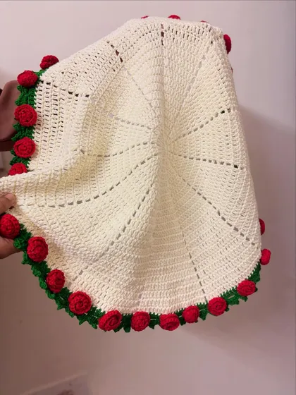 A view of the rose blanket being held, showing its generous size and the quality of the stitch work.