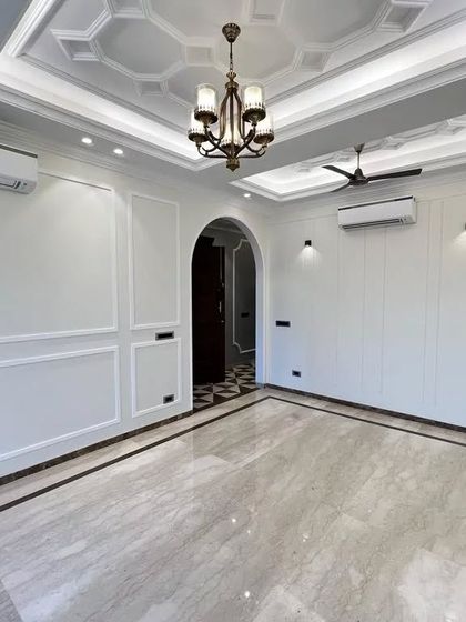 This view shows the drawing room opening up to the hallway through a grand arch. The consistent Italian marble flooring with a dark border ties the two spaces together seamlessly.