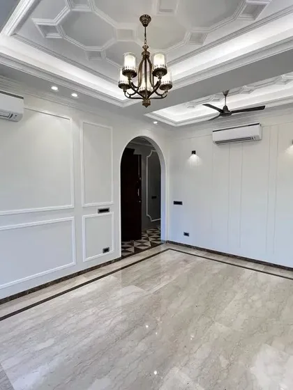 This view shows the drawing room opening up to the hallway through a grand arch. The consistent Italian marble flooring with a dark border ties the two spaces together seamlessly.